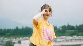 A photo of an Asian woman holding her right hand up to her right eye